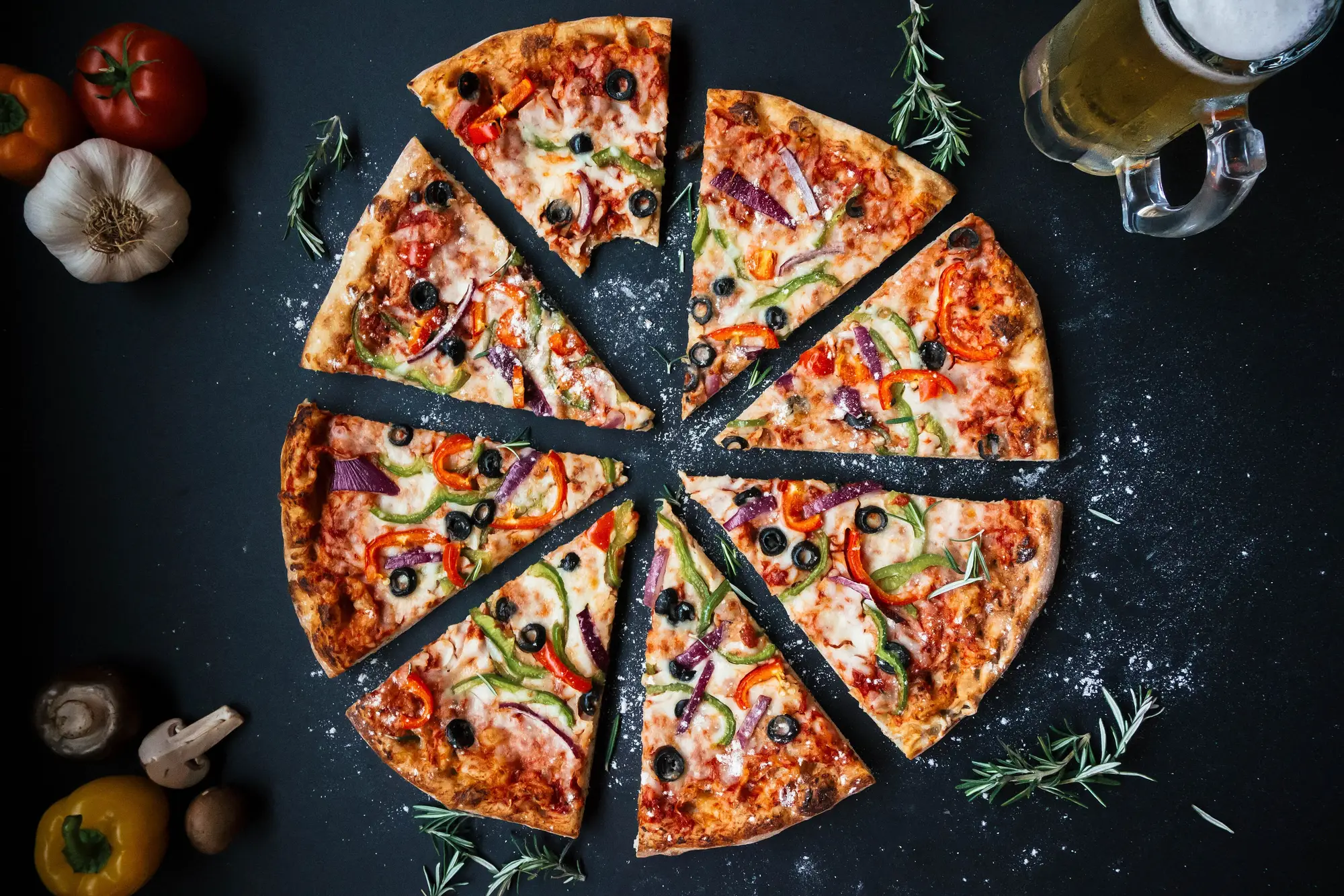 Three stone-baked pizzas on a dark table